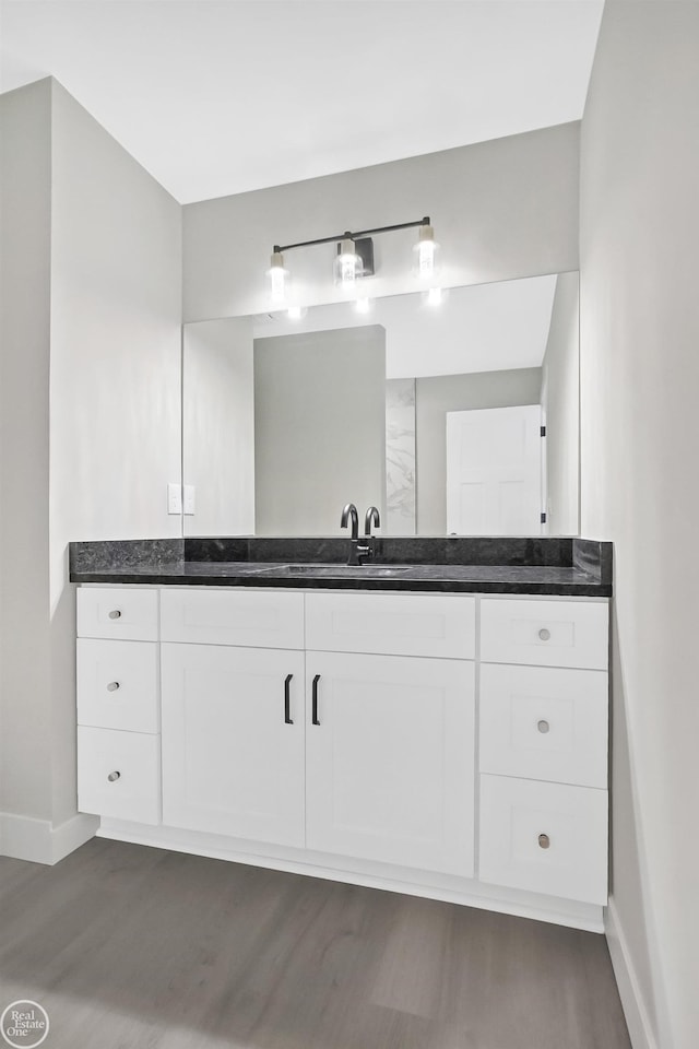 bathroom with wood finished floors, vanity, and baseboards
