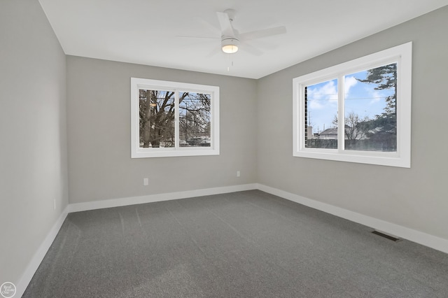 spare room featuring dark carpet, baseboards, and a ceiling fan