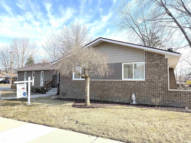 view of side of property with a lawn and brick siding