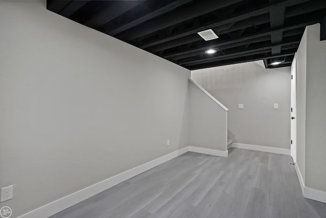 finished basement with baseboards, wood finished floors, and stairs
