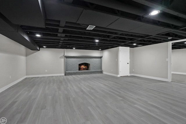 finished below grade area with visible vents, baseboards, wood finished floors, and a fireplace