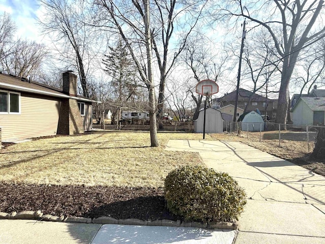 view of yard featuring fence, an outbuilding, a residential view, and a storage shed