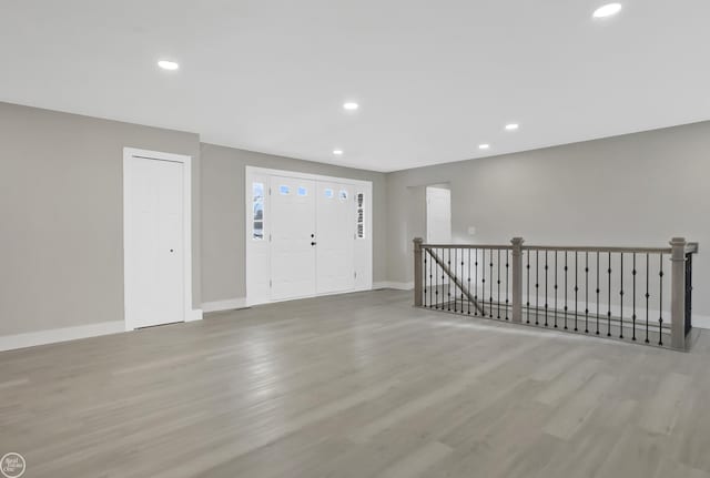 foyer entrance featuring baseboards, wood finished floors, and recessed lighting