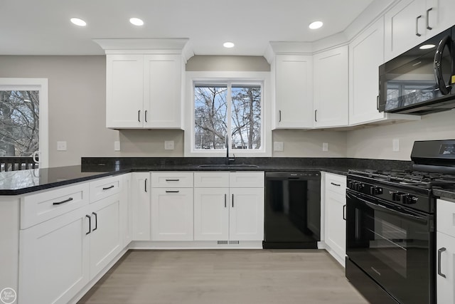 kitchen with a sink, black appliances, light wood-style floors, white cabinets, and a peninsula