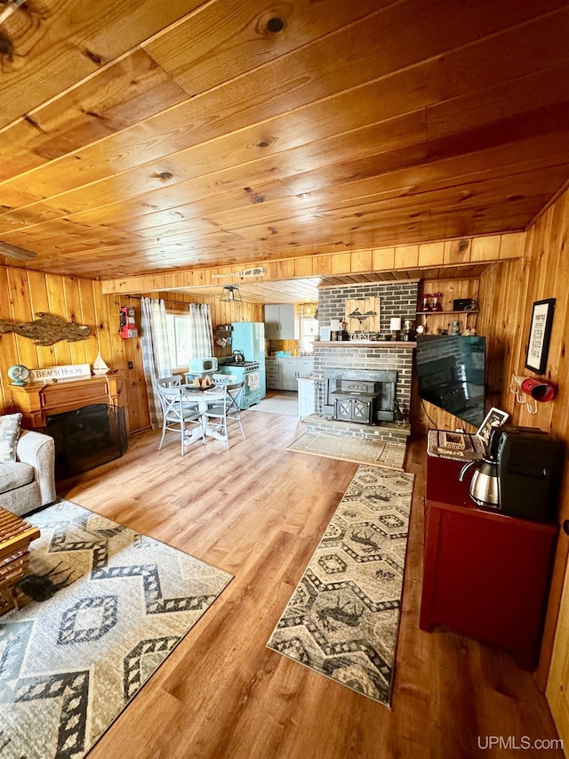 living room featuring wooden walls, wood finished floors, a fireplace, and wood ceiling