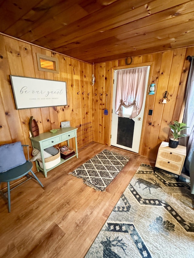 living area with wooden ceiling, wood finished floors, and wooden walls