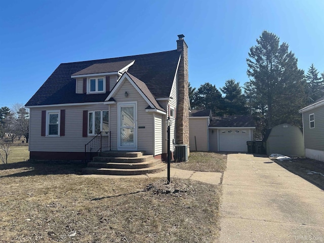 view of front of property featuring cooling unit, a detached garage, an outdoor structure, a chimney, and driveway