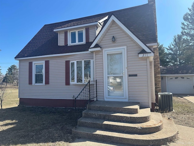 bungalow-style home with entry steps, a garage, and central AC unit