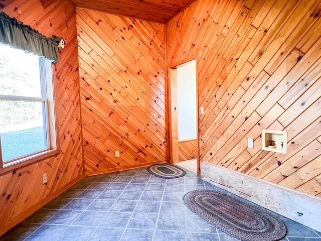 interior space with tile patterned floors and wooden walls