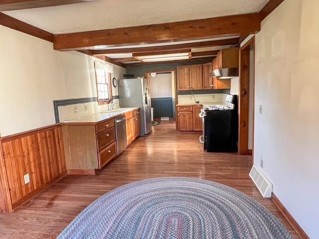 kitchen featuring wood finished floors, visible vents, appliances with stainless steel finishes, and wall chimney range hood