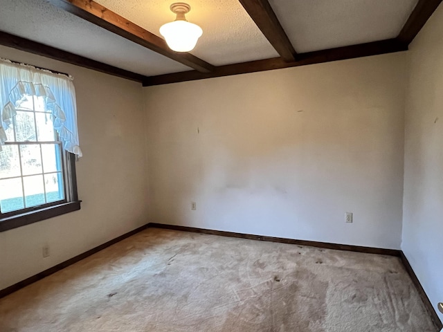 carpeted spare room featuring beamed ceiling, baseboards, and a textured ceiling