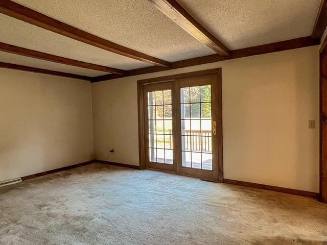 spare room featuring beam ceiling, carpet flooring, and a textured ceiling
