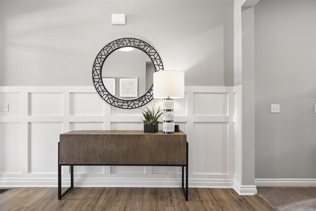 details with a wainscoted wall, wood finished floors, and a decorative wall