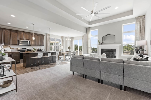living room featuring a ceiling fan, a glass covered fireplace, light wood finished floors, and recessed lighting