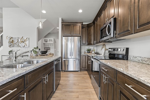 kitchen with light stone counters, stainless steel appliances, a sink, light wood-type flooring, and dark brown cabinetry