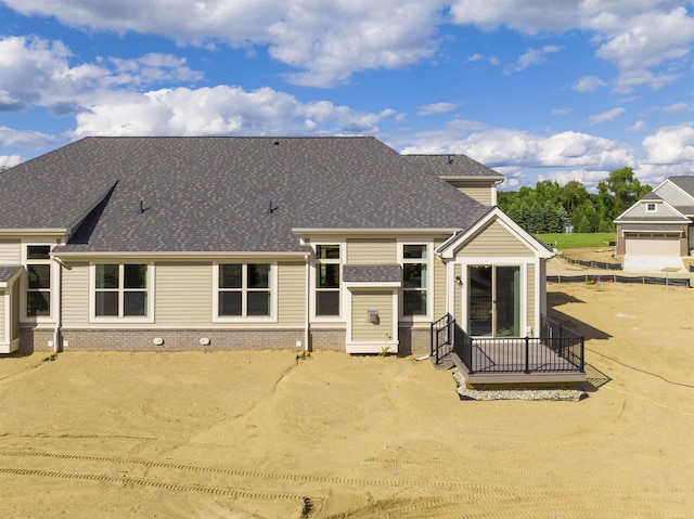 back of property with brick siding and roof with shingles