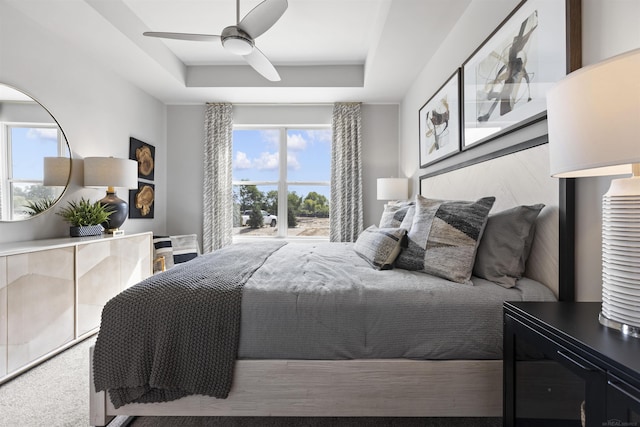 bedroom with ceiling fan and a raised ceiling