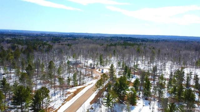 snowy aerial view featuring a forest view