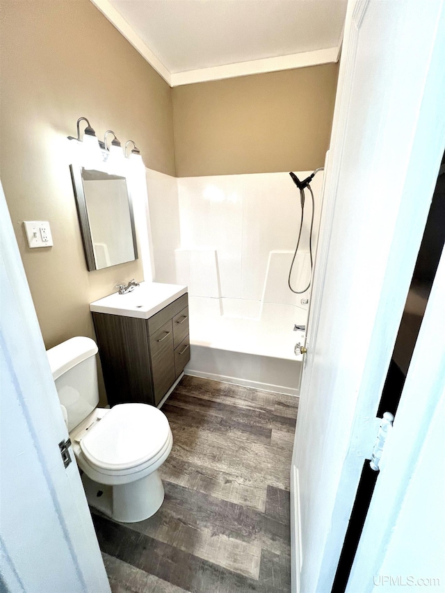 bathroom featuring crown molding, wood finished floors, vanity, tub / shower combination, and toilet