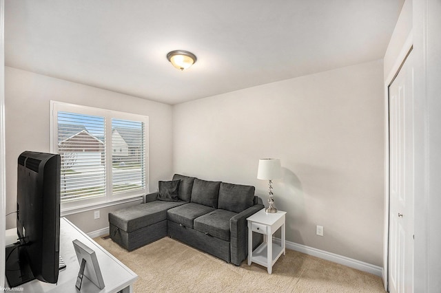 living area featuring baseboards and light colored carpet