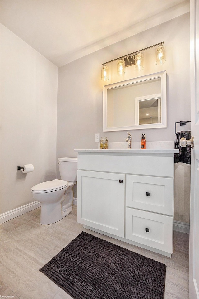 bathroom with wood finished floors, toilet, and baseboards