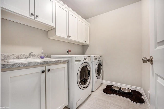 laundry room featuring baseboards, cabinet space, washer and clothes dryer, and a sink