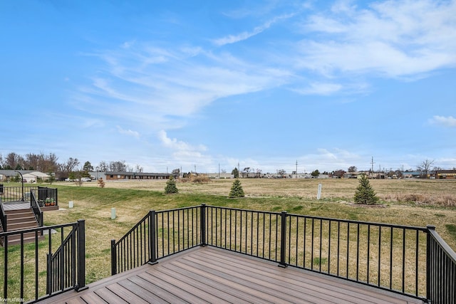 wooden terrace featuring a lawn and a rural view