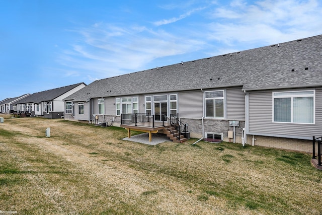 rear view of house featuring a lawn, a residential view, a deck, and a shingled roof