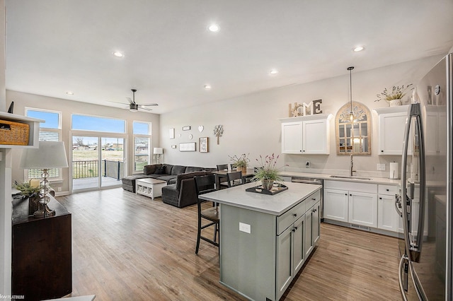 kitchen featuring a center island, a sink, open floor plan, light countertops, and freestanding refrigerator