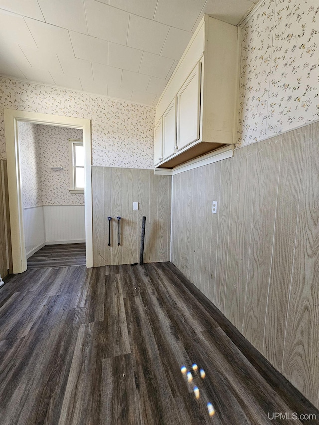 laundry room with wallpapered walls, dark wood-style floors, and wainscoting