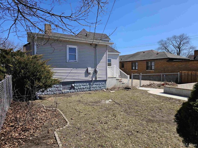 back of property featuring a fenced backyard and a chimney