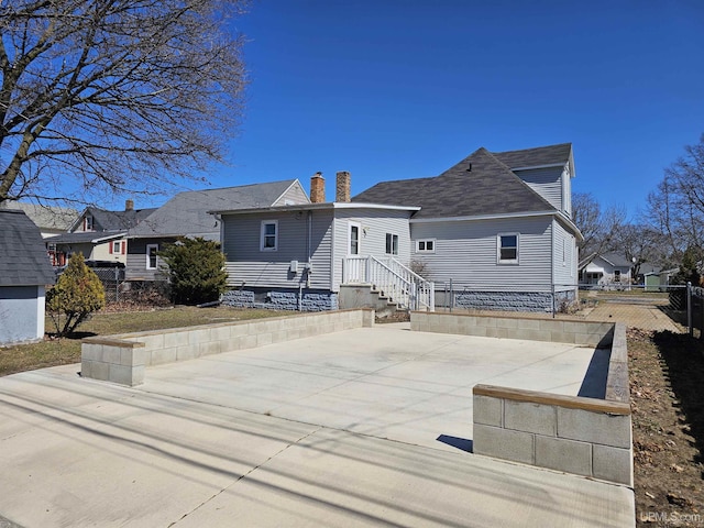 back of house featuring a patio area, a chimney, and fence
