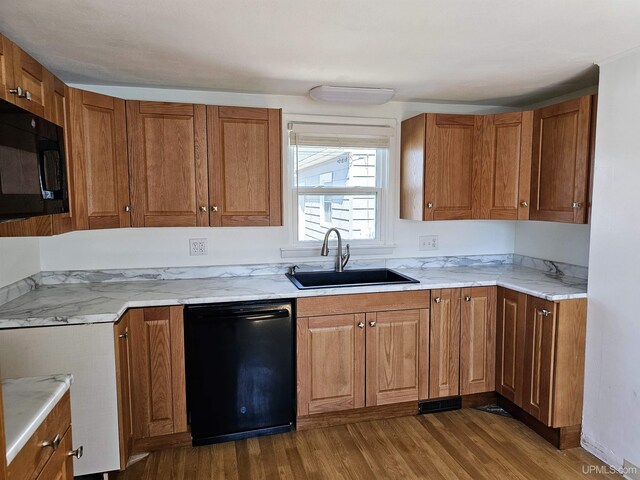 kitchen featuring dark wood-type flooring, brown cabinets, a sink, and black appliances