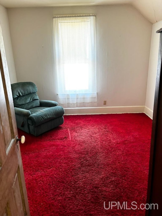 living area with vaulted ceiling, baseboards, and carpet floors