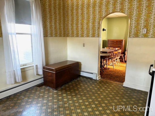 interior space with a baseboard radiator, arched walkways, and wallpapered walls