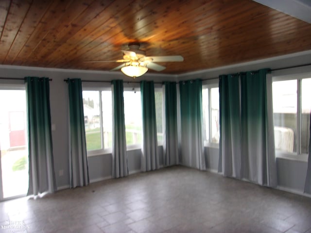 unfurnished room with baseboards, wood ceiling, and ceiling fan