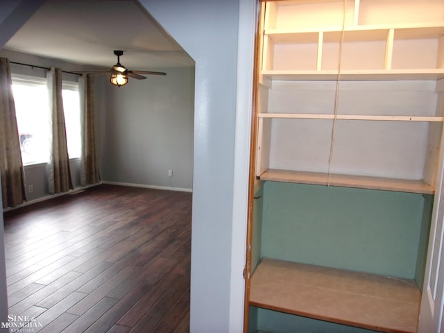 empty room featuring a ceiling fan, baseboards, and dark wood-style flooring