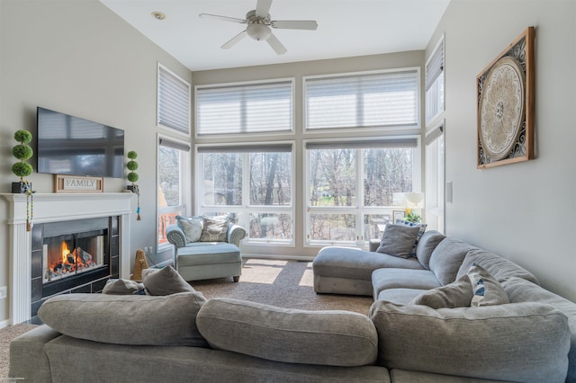 carpeted living room featuring a tiled fireplace and a ceiling fan