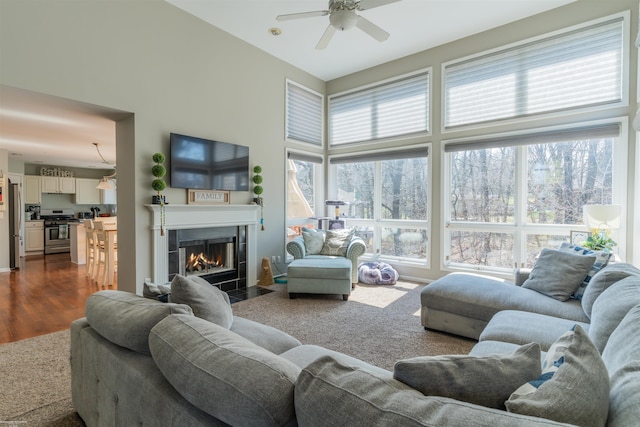 living room featuring a fireplace with flush hearth, dark wood-type flooring, and ceiling fan