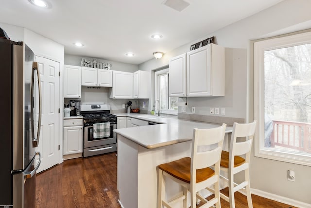 kitchen featuring a peninsula, a healthy amount of sunlight, stainless steel appliances, and a sink