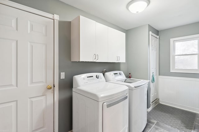 laundry room featuring cabinet space, tile patterned floors, a wainscoted wall, and separate washer and dryer