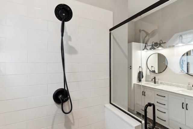bathroom featuring a tile shower, double vanity, and a sink
