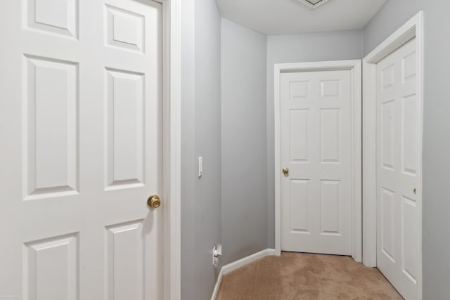 hallway with light colored carpet and baseboards