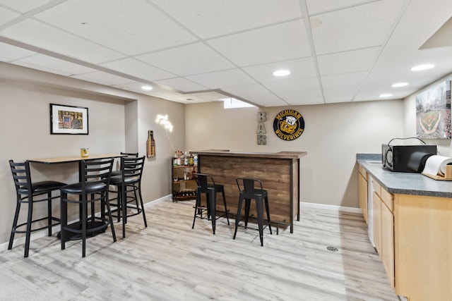 bar featuring black microwave, a dry bar, baseboards, and light wood-style flooring