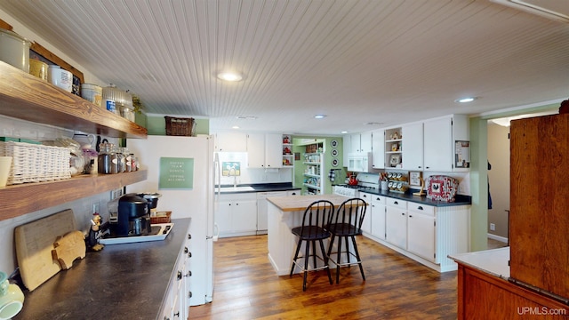 kitchen with white cabinets, recessed lighting, open shelves, dark countertops, and a kitchen island