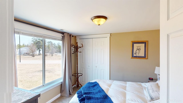 bedroom with a closet, baseboards, access to exterior, and light colored carpet