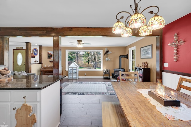 kitchen featuring a wood stove, open floor plan, white cabinetry, and dark stone countertops