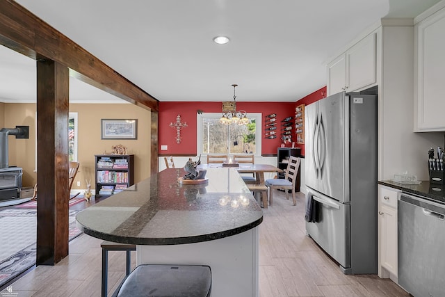 kitchen with white cabinets, an inviting chandelier, light wood-type flooring, and appliances with stainless steel finishes