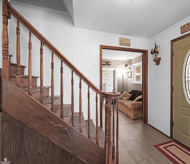 foyer featuring wood finished floors, stairs, and ornamental molding