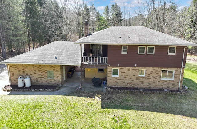 rear view of property featuring a chimney, a shingled roof, a yard, a patio, and brick siding